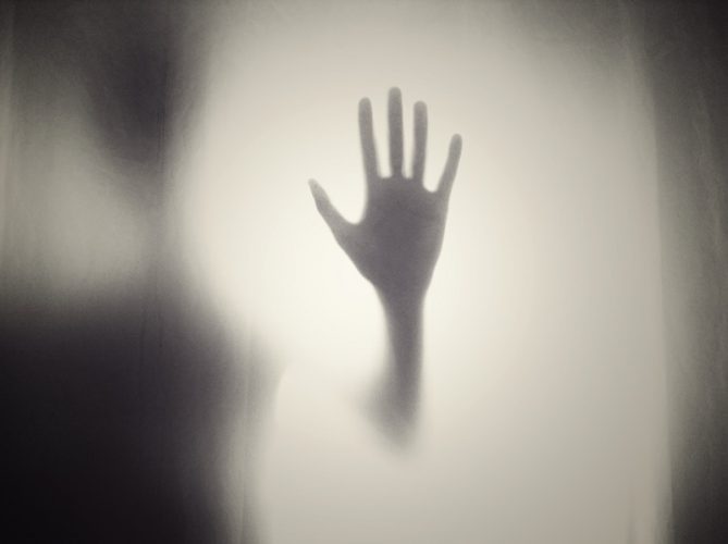 A dark hand pressed against a glass