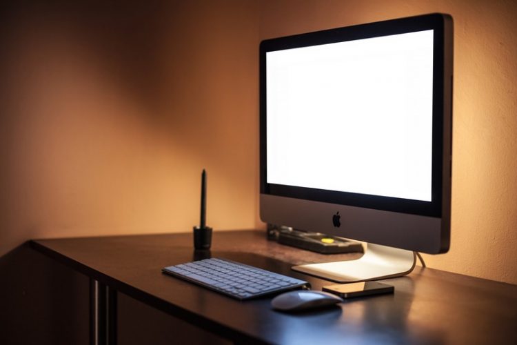 An iMac with a glowing screen in an ill lit room
